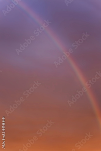 Rainbow in a dramatic sunset sky. Great scenery. Space for text. Background. Blurred. Vertical.