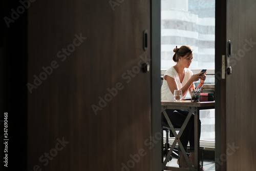 Woman Working In Corporate Office Sending Email With Phone