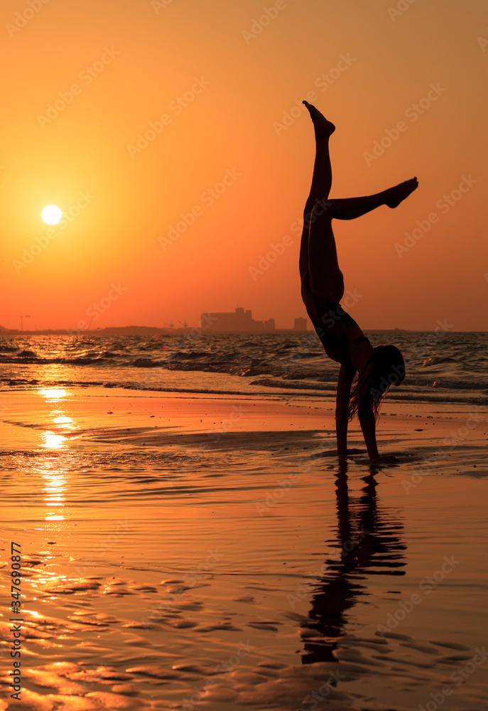 Woman Practicing Handstand At Beach Against Clear Sky During Sunset