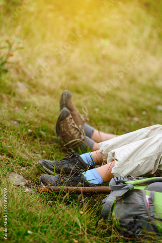 Closeup of kid's legs resting on green grass after hiking in Carpathians