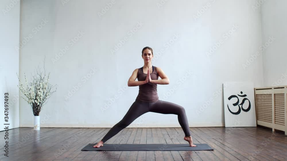 Young and fit woman practicing yoga indoor in the class. Stretching exercise in the day light. Sport, fitness, health care and lifestyle.