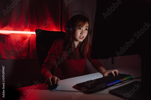 Cuadro en lienzo Pro player gamer young asian woman playing online video game shooting fps tournament ranking cyber internet at night red neon light room with gaming headset and keyboard on championship event