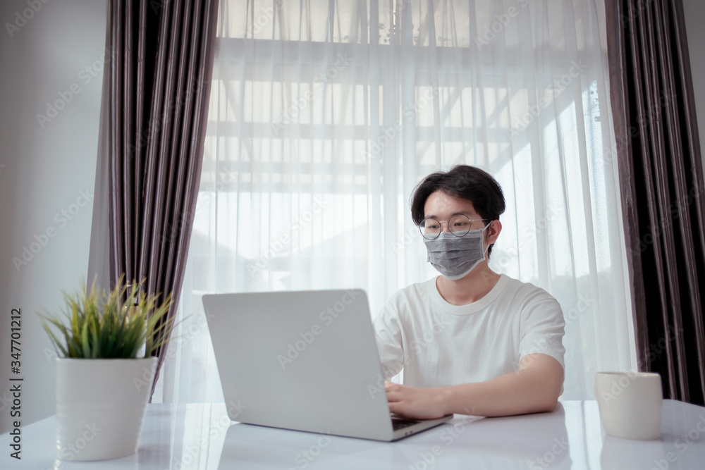 Asian man wearing mask working from home with laptop computer self isolation from society to reduce risk, quarantine prevention coronavirus, covid-19 and study e-learing online education technology. Asian man wearing mask working from home with laptop computer self isolation from society to reduce risk, quarantine prevention coronavirus, covid-19 and study e-learing online education technology.