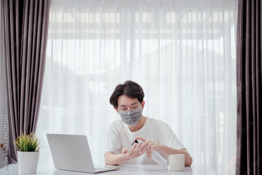 Asian man wearing mask pump hand gel alcohol cleaning sanitizer working from home with laptop computer prevent the spread of coronavirus quarantine workplace with protective stay home. Asian man wearing mask pump hand gel alcohol cleaning sanitizer working from home with laptop computer prevent the spread of coronavirus quarantine workplace with protective stay home.