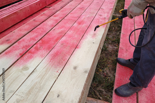 The worker applies a protective liquid, spoilage and rotting liquid on wooden boards.