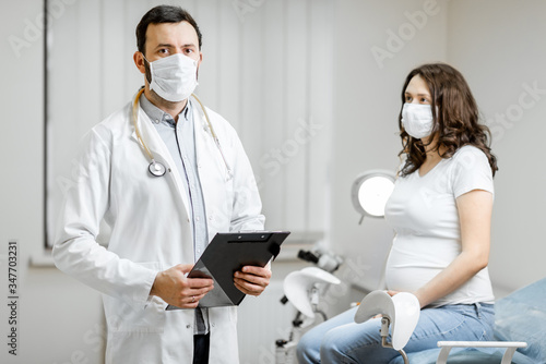 Portrait of a doctor with a pregnant woman in medical masks during an examinations. Concept of new rules for the use of masks in medicine after or during a pandemic