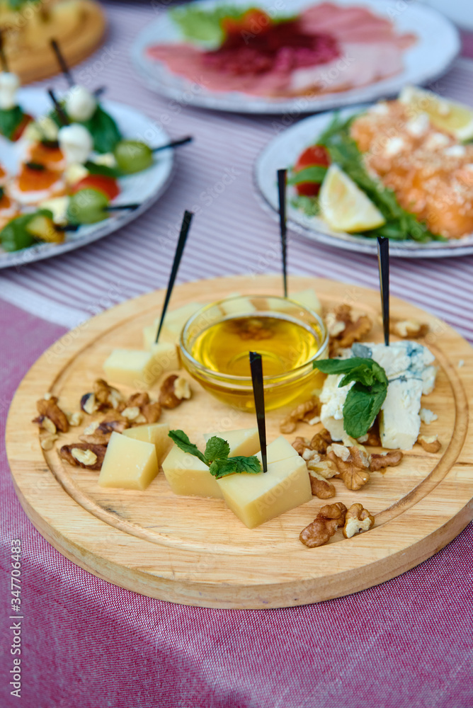 Wood board with assortment of cheese, nuts and honey on dinner table. Cheese plate Wood board with assortment of cheese, nuts and honey on dinner table. Cheese plate