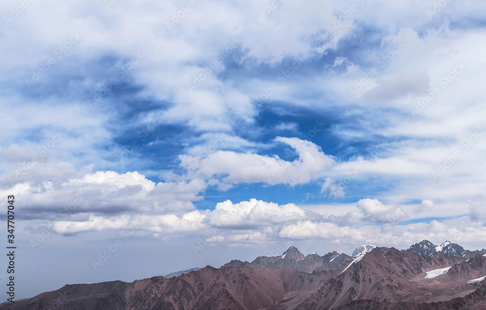Majestic crests of the mountains with epic romantic blue sky with expressive clouds