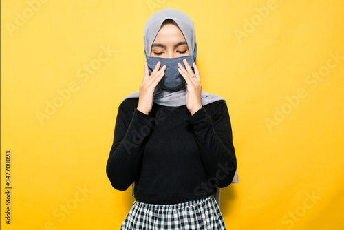 Asian woman wearing mask and holding mouth
