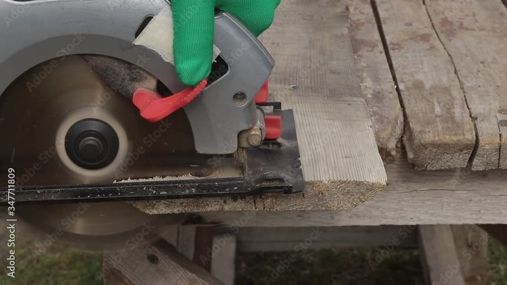 joiner sawing a wooden board with an electric saw joiner sawing a wooden board with an electric saw