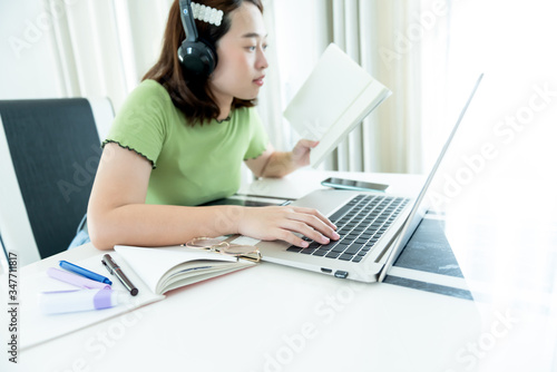 Blurred soft images of An Asian female student, 22 years old, Using a notebook computer For studying online from home, duing self quarantine from the spread of germs, to New normal concept.