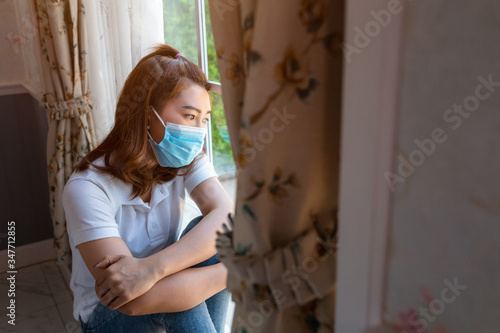 Coronavirus. Sick woman of corona virus looking through the window and wearing mask protection and recovery from the illness in home. Quarantine. Patient isolated to prevent infection. new normal.. photo