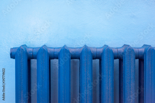 Cast-iron blue radiator for heating hanging on the wall.