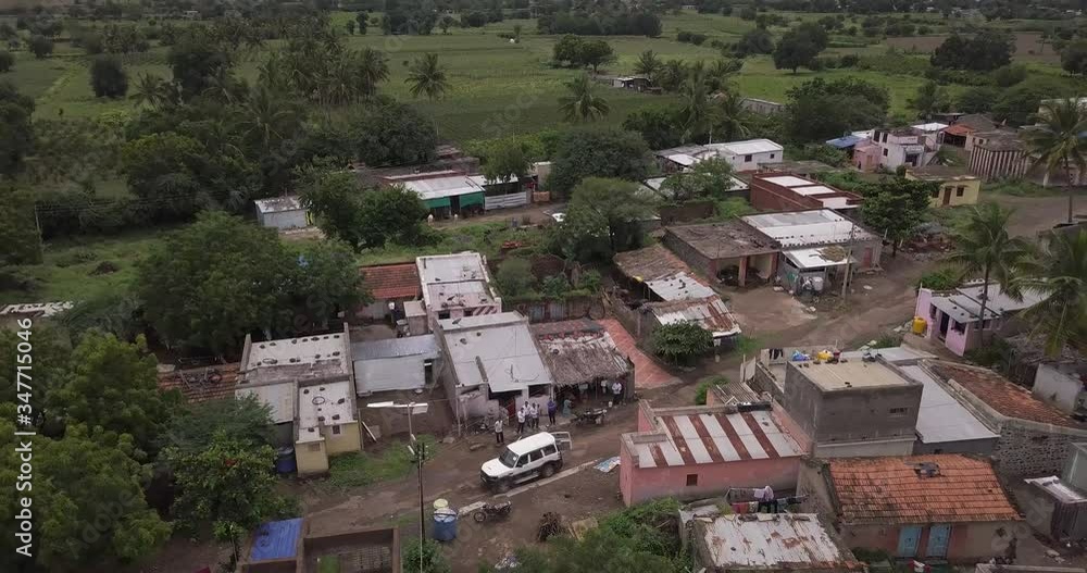 Aerial tilt shot of small village in the rural landscape of Karnataka, India with wind farm in the background. Aerial tilt shot of small village in the rural landscape of Karnataka, India with wind farm in the background.
