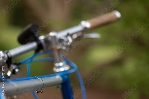 Detail of a beautiful customized retro bicycle focusing on the handlebar with a blurry park and trees in the background