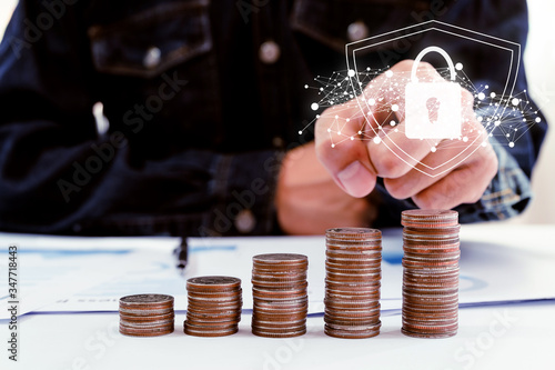 businessman sitting and pointing on coin stack with report on white desk in office. save money and management financial concept. gold success business.