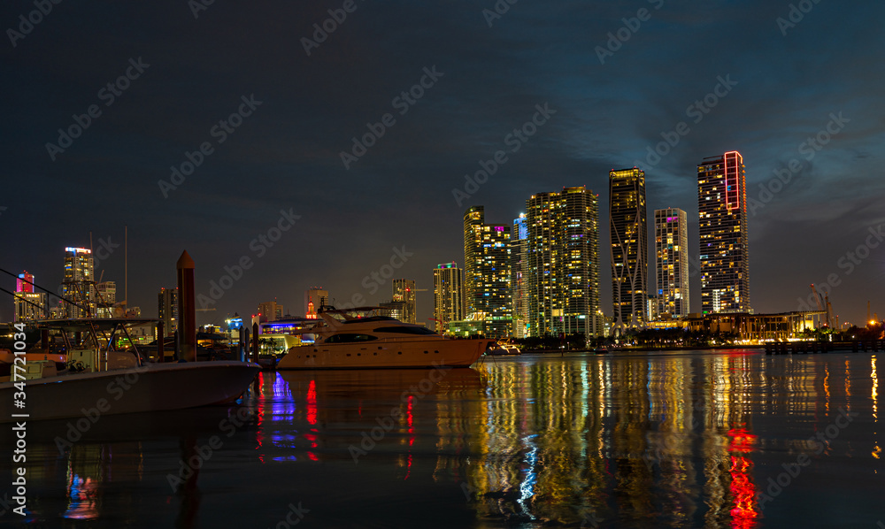 Fototapeta premium Miami city skyline panorama at dusk with urban skyscrapers and bridge over sea. Miami downtown view at night.