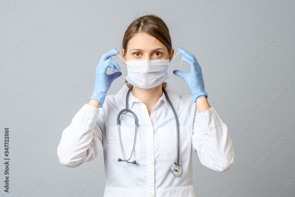 Portrait of doctor putting sterile mask isolated on gray Portrait of doctor putting sterile mask isolated on gray