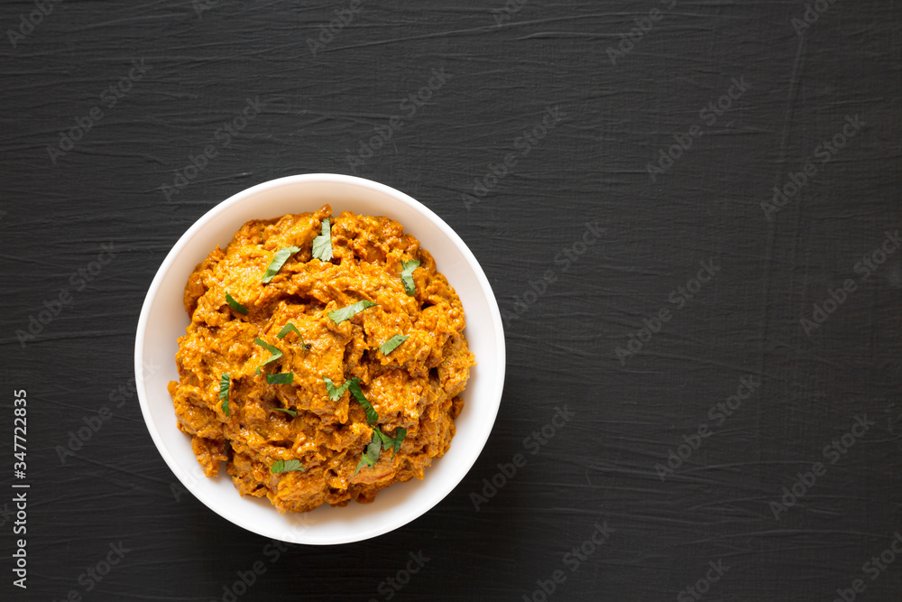 Homemade Chicken Tikka Masala in a white bowl on a black background, top view. Flat lay, overhead, from above. Copy space. Homemade Chicken Tikka Masala in a white bowl on a black background, top view. Flat lay, overhead, from above. Copy space.