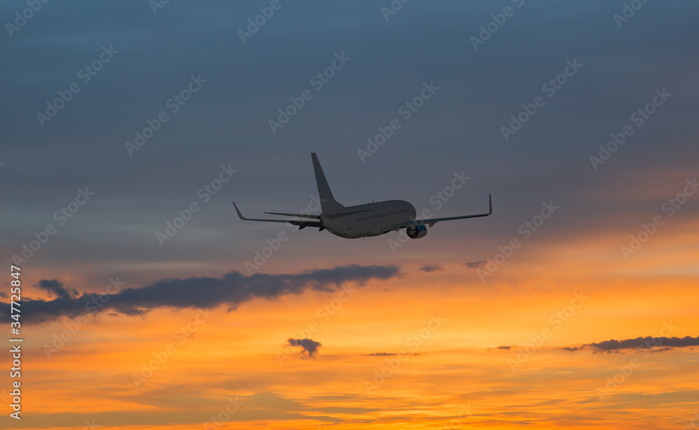 Obraz premium Airplane flying above tropical sea at sunset
