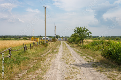 The dirt road among the fields leads to the gas distribution station