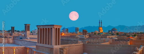 Historic City of Yazd with famous wind towers in the background full moon at twilight blue hour- YAZD, IRAN 