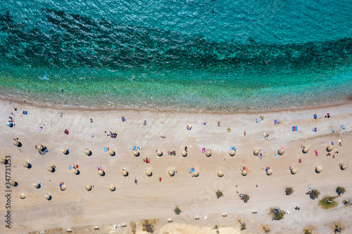 Topdown Luftaufnahme des Strandes von Glyfada in Athen, Griechenland, mit smaragdem Meer, feinem Sand und Sonnenschirmen