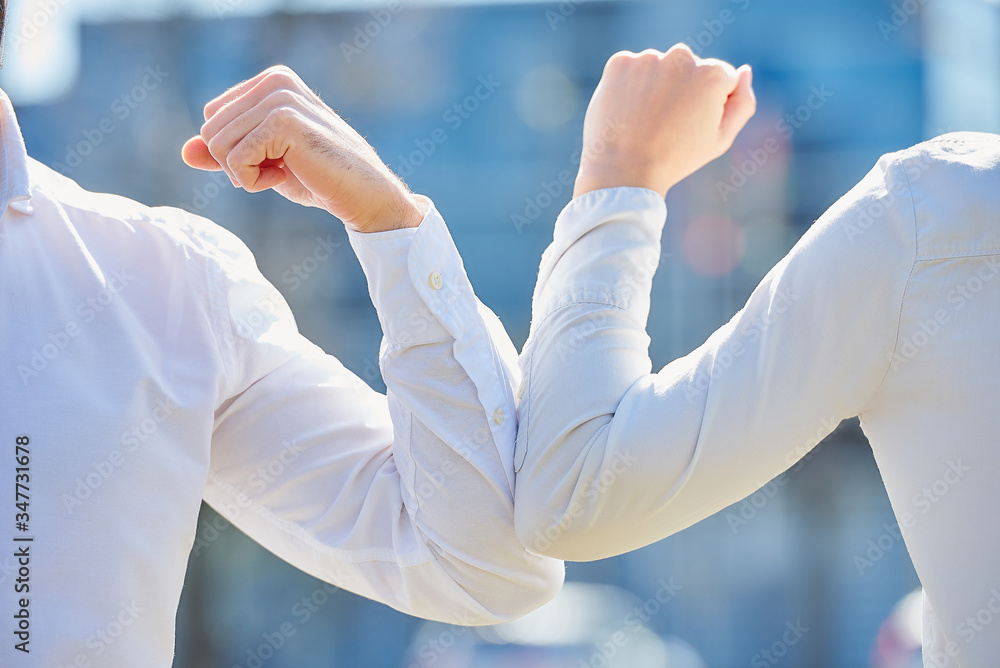A close-up photo of elbow bumping. Elbow greeting to avoid the spread of coronavirus (COVID-19). Colleagues meet with bare hands. Instead of greeting with a hug or handshake, they bump elbows. A close-up photo of elbow bumping. Elbow greeting to avoid the spread of coronavirus (COVID-19). Colleagues meet with bare hands. Instead of greeting with a hug or handshake, they bump elbows.