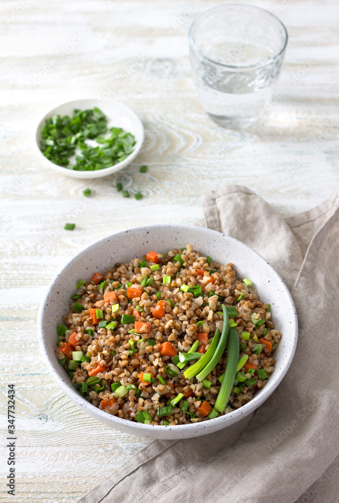 Delicious vegan buckwheat with vegetables and green onions on a light wooden background. Healthy homemade food Delicious vegan buckwheat with vegetables and green onions on a light wooden background. Healthy homemade food