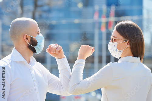 Elbow bumping. Elbow greeting to avoid the spread of coronavirus (COVID-19). A woman and a man meet in the street with bare hands. Instead of greeting with a handshake, they bump elbows. photo