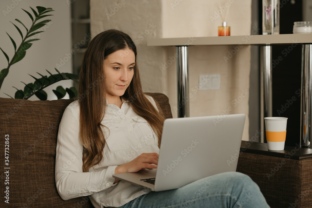 Remote work. A caucasian woman working remotely on her laptop. A businesswoman working from home on the couch. Remote work. A caucasian woman working remotely on her laptop. A businesswoman working from home on the couch.