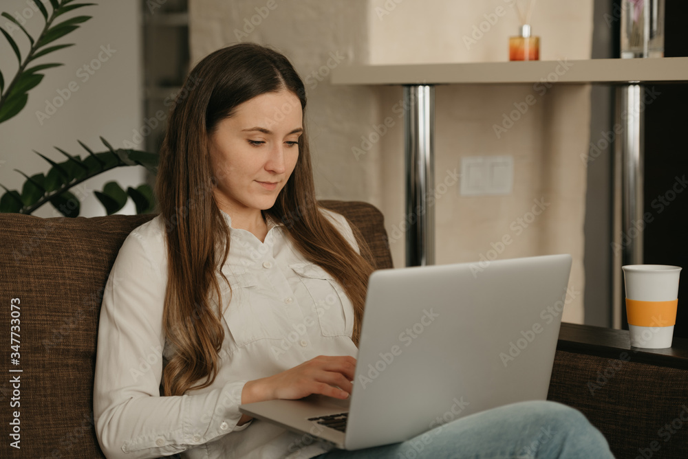 Remote work. A caucasian woman working remotely on her laptop. A businesswoman works from home sitting on the couch.