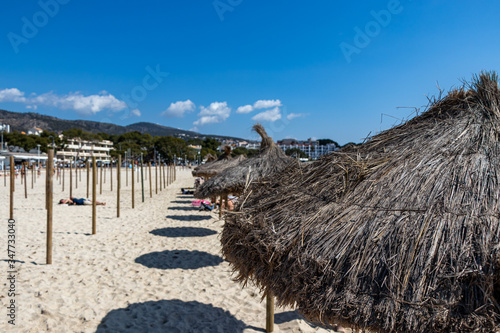 row of beach umbrellas on Palmanova beach in Calvia Bol ses Taules Mallorca, spain