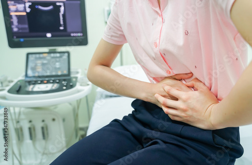 Young woman with stomach ache while sitting on the bed in ultrasound room for diagnosis  Medical concept