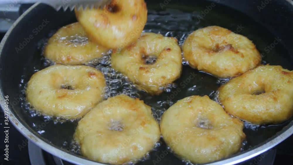The kuih keria is being fried using cooking oil in a hot pan. It is a