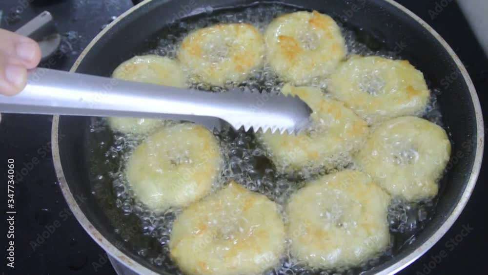 The kuih keria is being fried using cooking oil in a hot pan. It is a traditional Malay cake. Made from the main ingredients of mashed sweet potatoes and flour. Cover with sugar after frying. The kuih keria is being fried using cooking oil in a hot pan. It is a traditional Malay cake. Made from the main ingredients of mashed sweet potatoes and flour. Cover with sugar after frying.