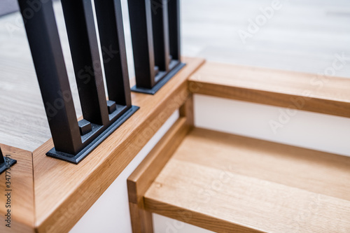 Metal handrails and wooden stairs. Combination of types of materials. Black brushed metal. Loft and high-tech