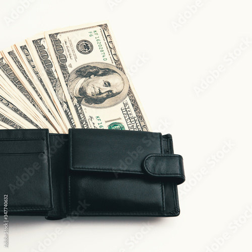 A black wallet with dollars in it on a white background.
