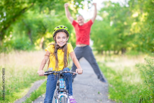 Activity leisure family. Happy father rejoices that his daughter learned to ride a bike