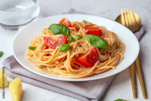 Pasta with tomatoes and basil on a light background