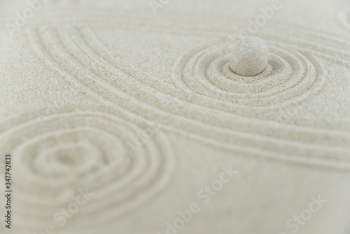 Zen garden. Pyramids of white and gray zen stones on the white sand with abstract wave drawings. Concept of harmony  balance and meditation  spa  massage  relax.