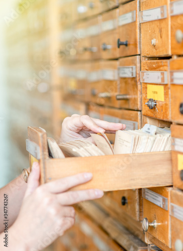 Student searches cards in old wooden card catalogue