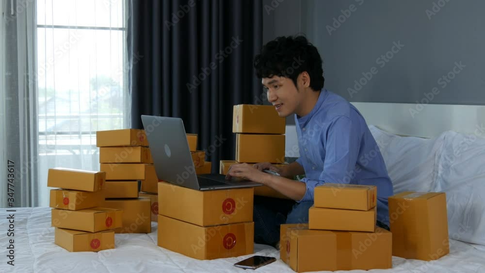 successful man working and using laptop computer to selling product online on a bed at home successful man working and using laptop computer to selling product online on a bed at home