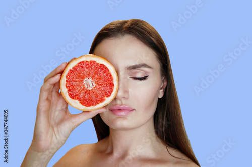 Young woman with grapefruit cut in half, healthy life concept . photo of attractive girl holding a cut piece of pomelo in her hands. Healthy and proper nutrition
