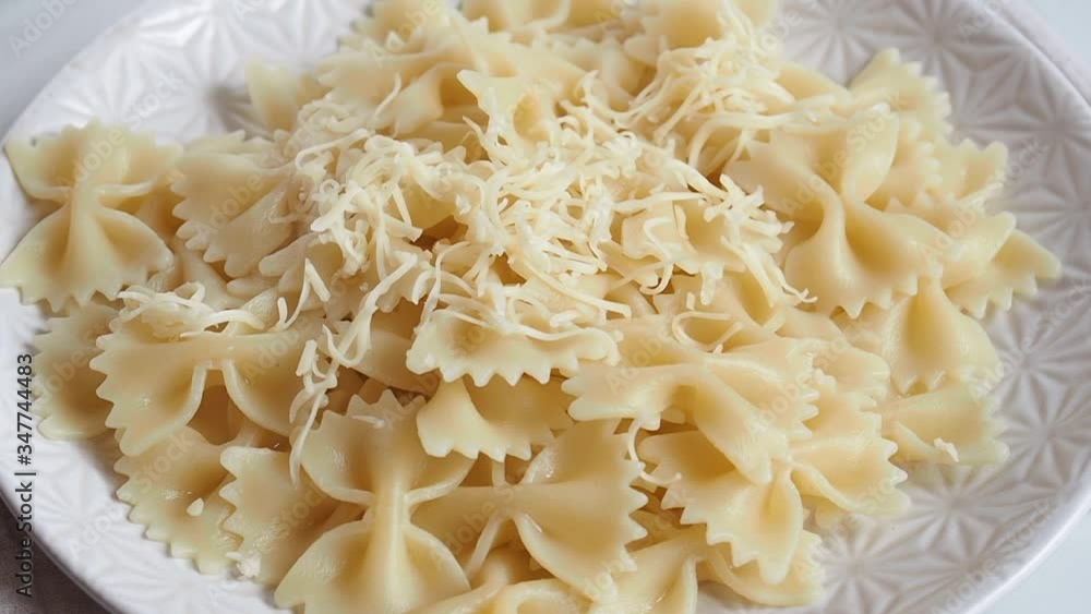 The cook sprinkles with finely grated cheese Italian pasta macaroni bows farfalle. The cook sprinkles with finely grated cheese Italian pasta macaroni bows farfalle.