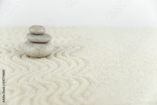 Zen garden. Pyramids of white and gray zen stones on the white sand with abstract wave drawings. Concept of harmony, balance and meditation, spa, massage, relax.