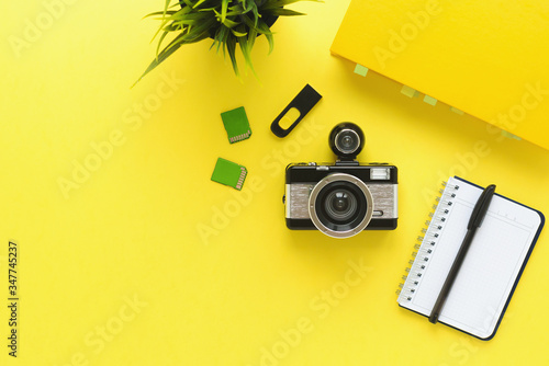 camera, textbook, notebook, pen and memory cards on a yellow background, the concept of learning 