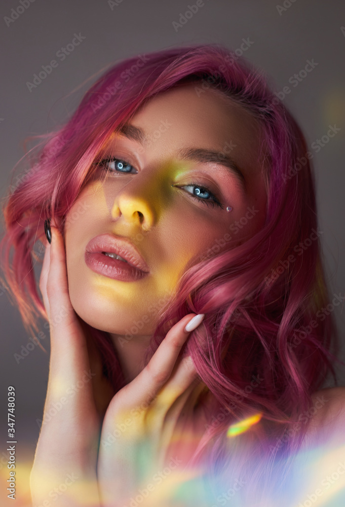 Beauty portrait woman with pink hair, creative vivid coloring. Bright colored highlights and shadows color on the face, a girl with jewelry. Dyed hair in the wind