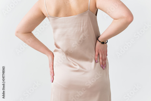 Fashion photo of young lady in elegant evening dress on white background, close-up back view.