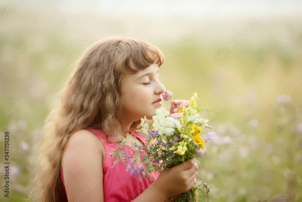 a pretty girl in a pink blouse sniffs a bouquet of flowers in the field. sunset in the background. portrait. close up. a pretty girl in a pink blouse sniffs a bouquet of flowers in the field. sunset in the background. portrait. close up.
